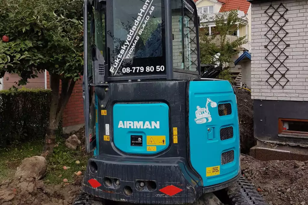 Minigrävare vid en villa under dräneringsarbete